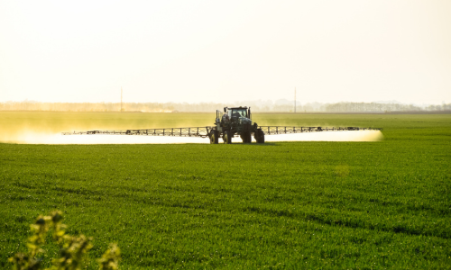 Tractor chemical spraying a field